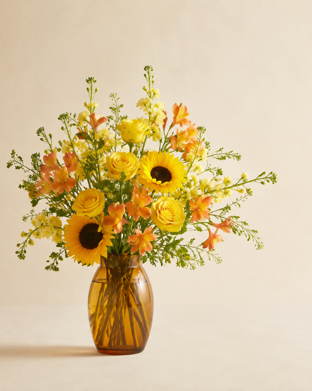 Amber Meadow Memories sympathy vase with yellow roses, sunflowers, orange alstroemeria, and yellow stock in an amber glass vase