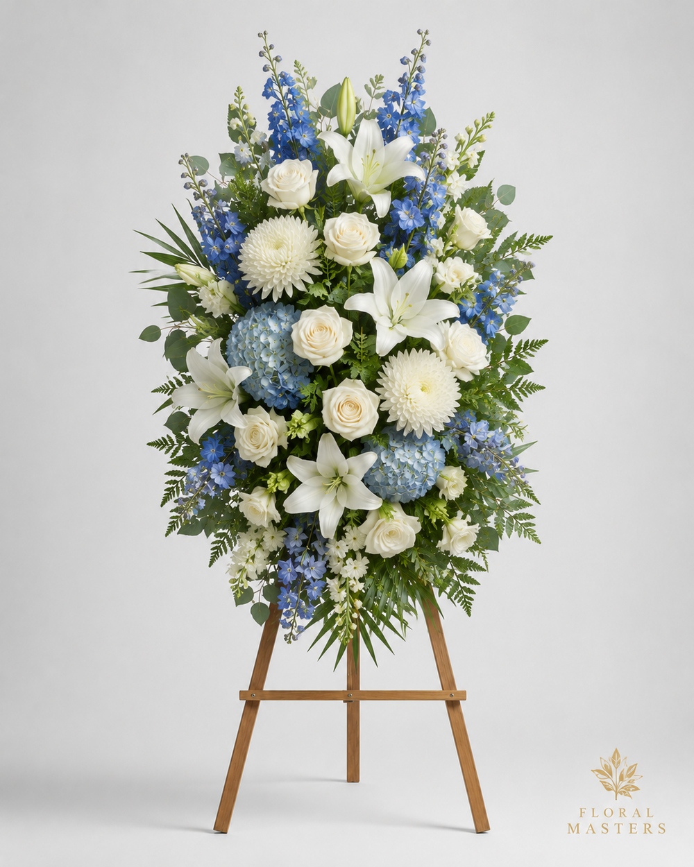 Blue and white funeral standing spray with lilies, roses, hydrangea and delphinium on wooden easel