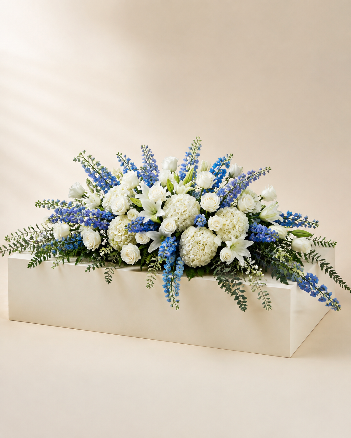 Blue Stillwater Half-Casket Spray with white roses, blue delphinium, hydrangeas, and lilies