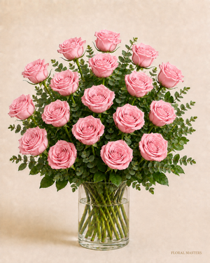 18 soft pink roses with greenery in a clear glass vase