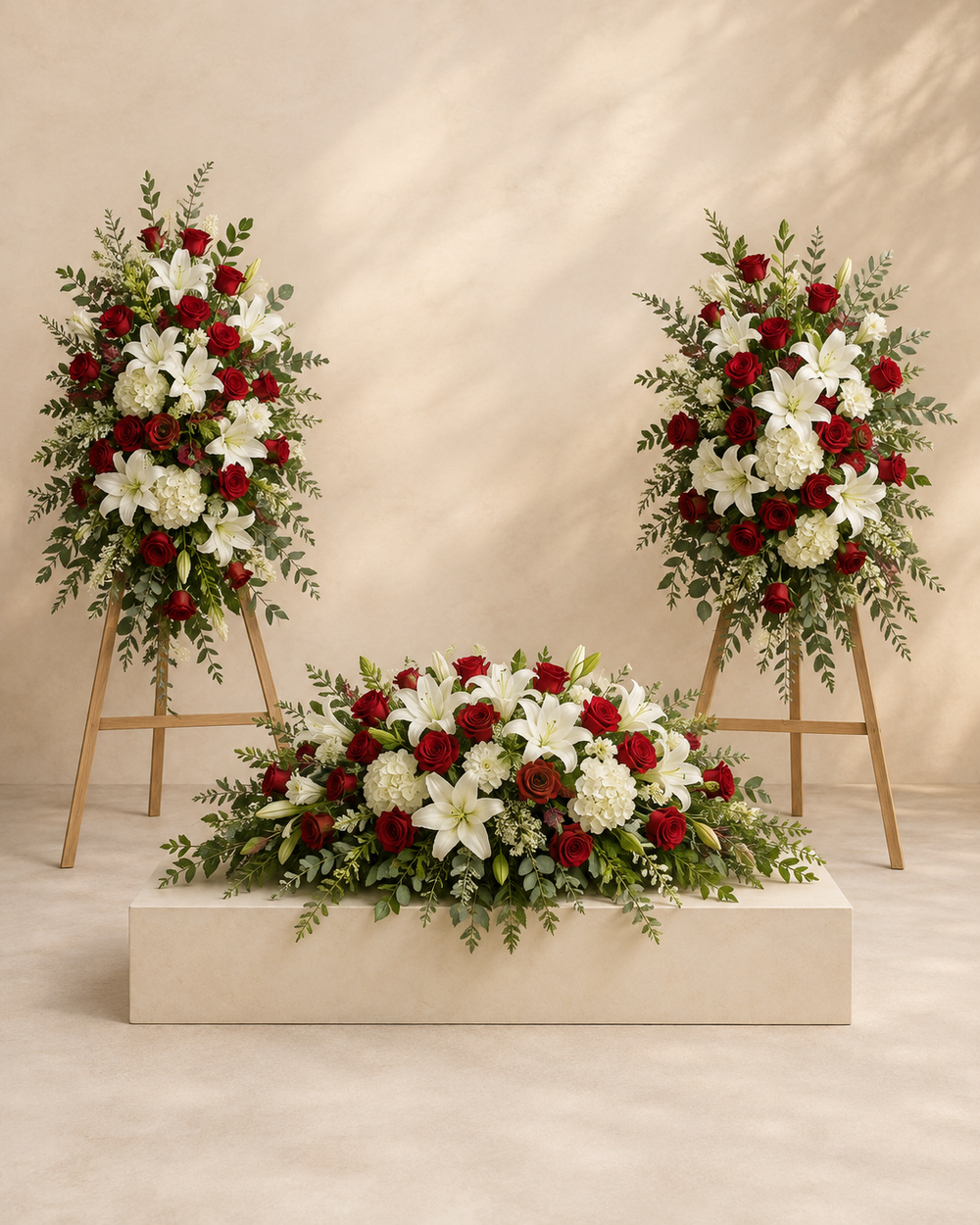 Crimson Keepsake Tribute Trio with red and white half-casket spray and two standing sprays