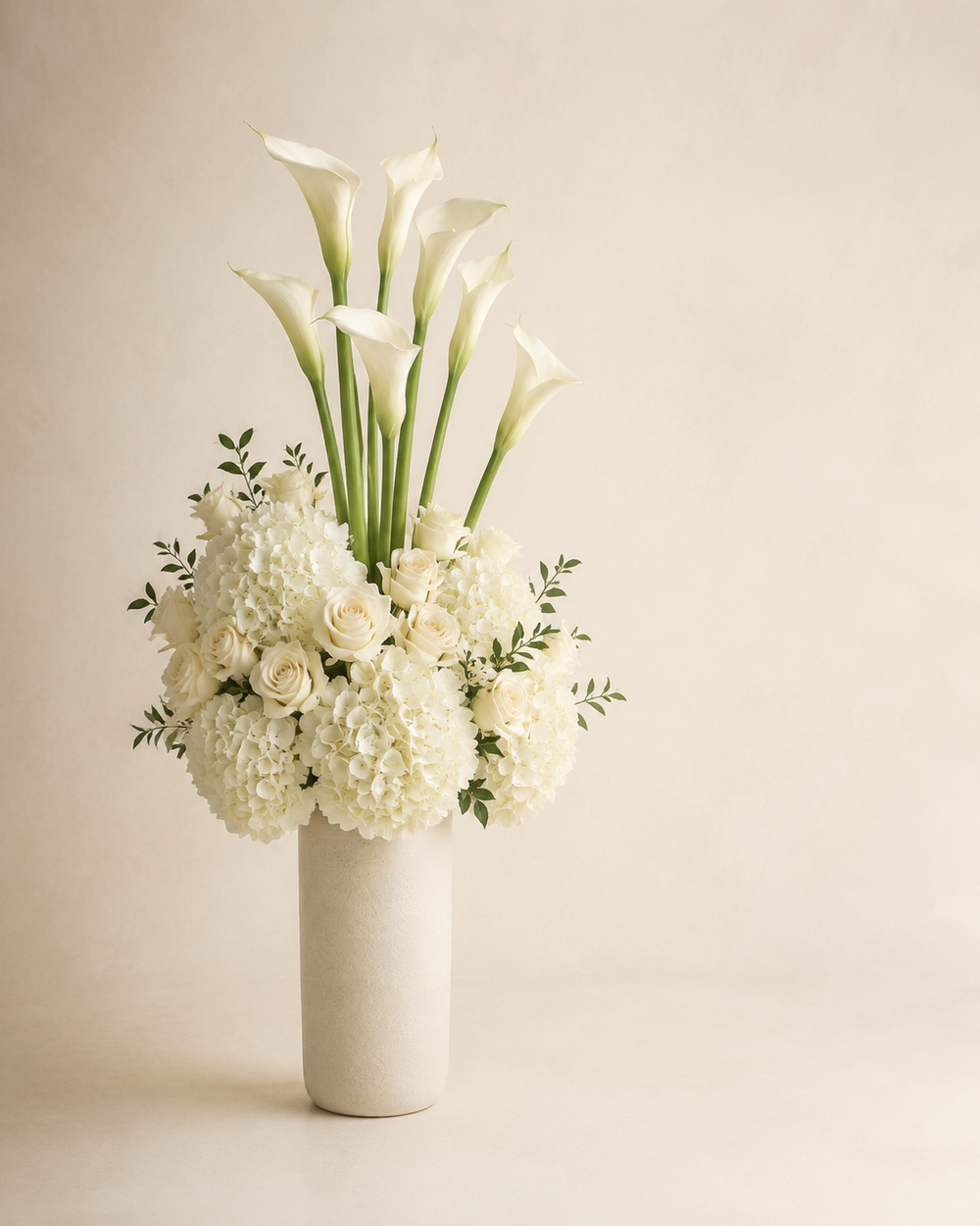 Ivory Calla Column with white calla lilies, ivory roses, and white hydrangeas in a tall alabaster ceramic vase