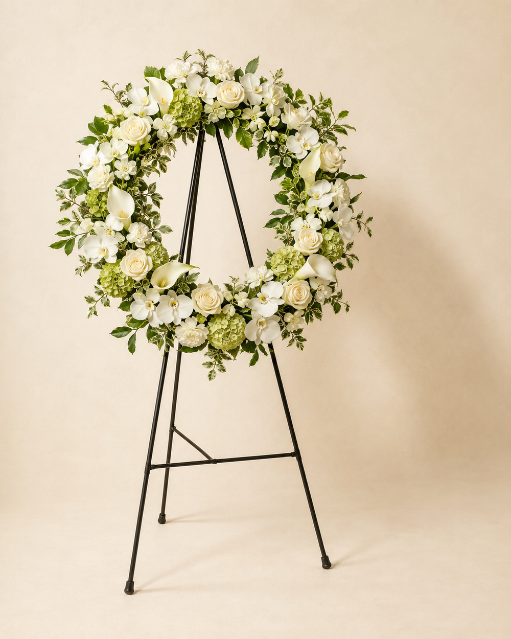 Orchid Light memorial wreath with white roses, dendrobium orchids, calla lilies, carnations, green hydrangea, and variegated foliage on an easel
