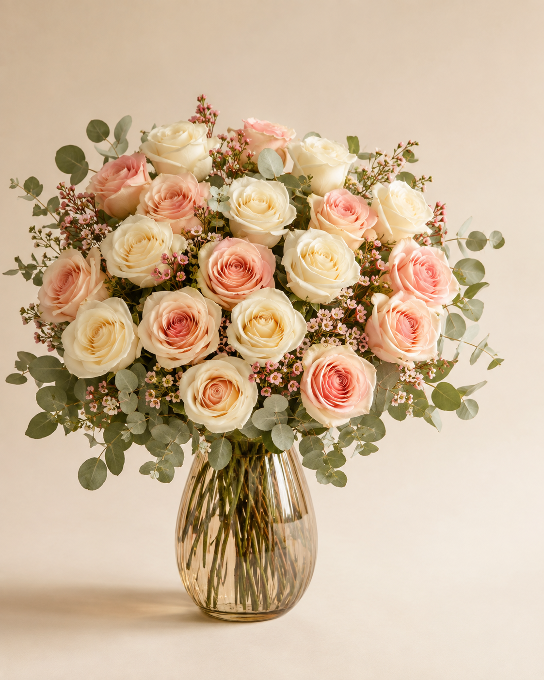 Rosé and Cream Twenty-Four blush and ivory roses in a champagne glass vase